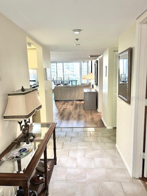 A hallway with tile flooring leads to a living area featuring wood floors and furniture — 1095 GULF OF MEXICO DRIVE UNIT 104, LONGBOAT KEY, FL