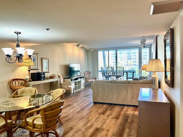 A living and dining area features wood-look flooring, a chandelier, and a large window wall — 1095 GULF OF MEXICO DRIVE UNIT 104, LONGBOAT KEY, FL