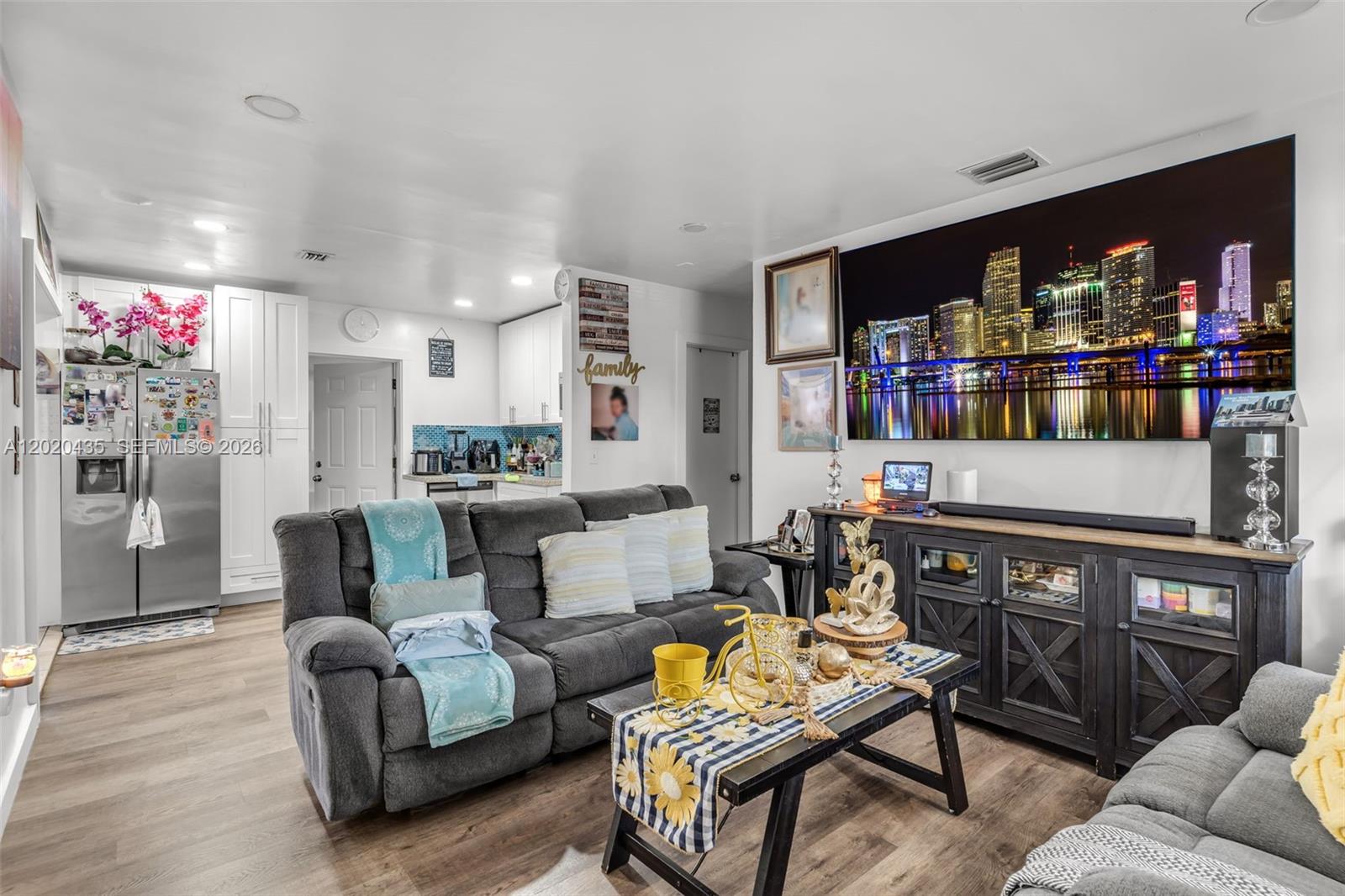 A living room features a grey sofa, a coffee table, and a large city skyline print — 13075 NW 16th Ave, North Miami FL 33167, NORTH MIAMI, FL