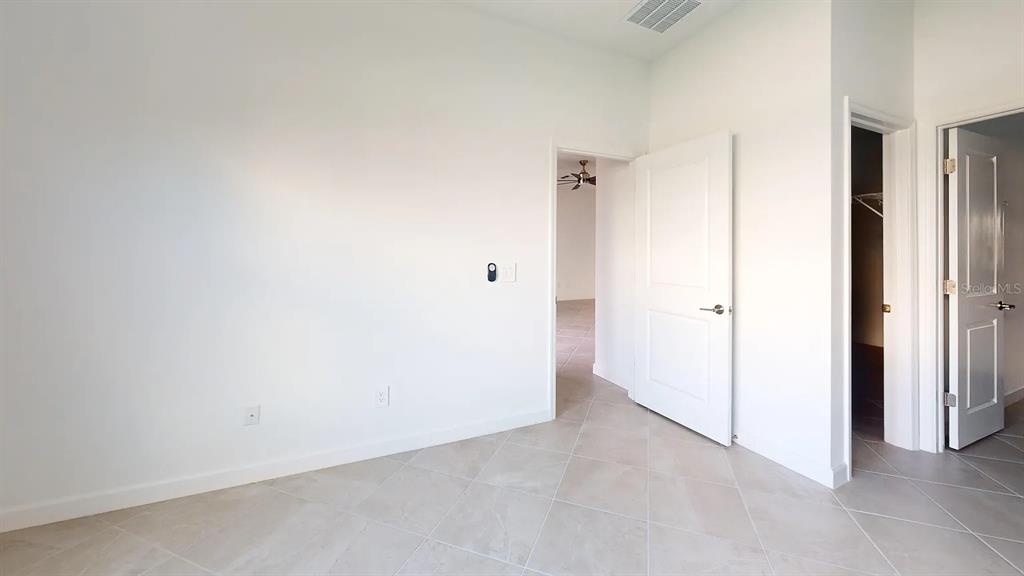 An empty room with white walls, tile flooring, and two open doorways — 8535 SAINT KITTS CIRCLE, ENGLEWOOD, FL