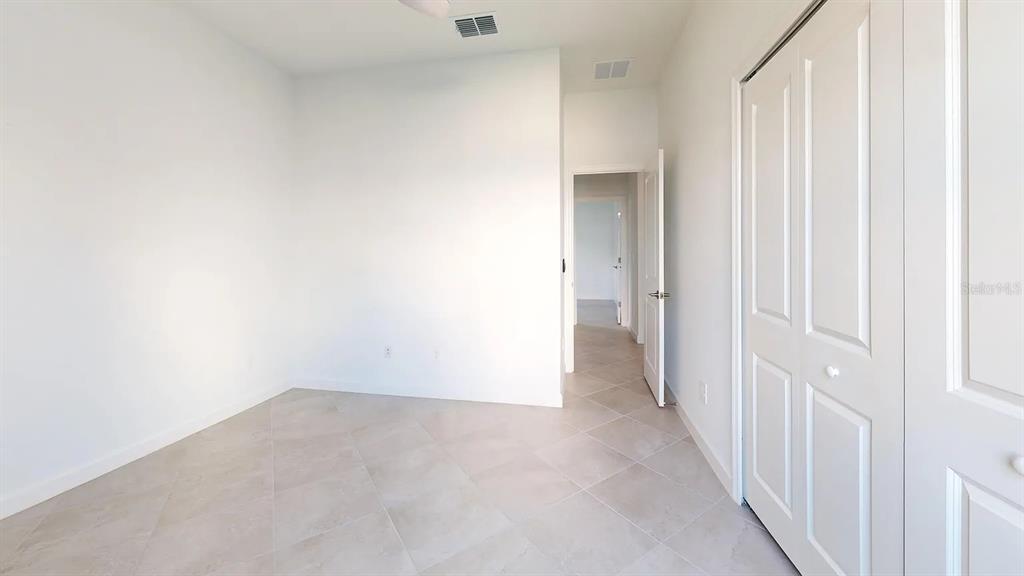 An empty room with white walls, tile flooring, and a white double-door closet — 8535 SAINT KITTS CIRCLE, ENGLEWOOD, FL