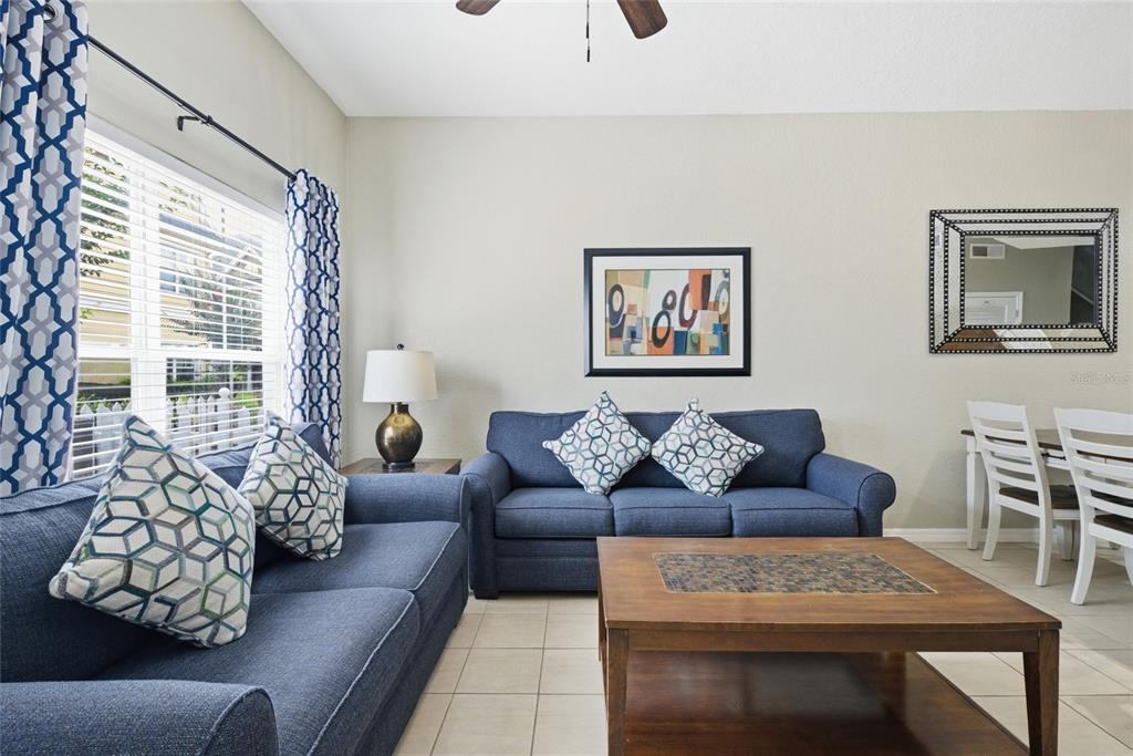 A living room features two blue sofas, a wooden coffee table, and patterned window curtains — 4562 JONAFREE LANE UNIT 106, KISSIMMEE, FL