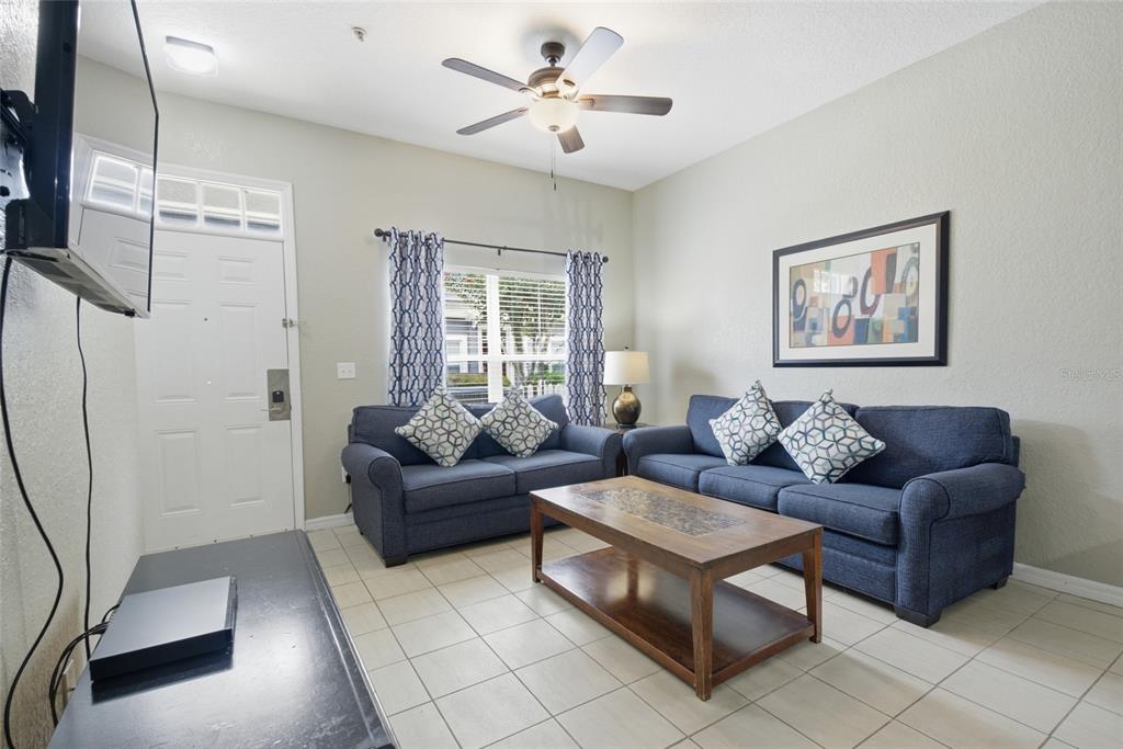 A living room features two blue sofas, a wooden coffee table, and tile flooring — 4562 JONAFREE LANE UNIT 106, KISSIMMEE, FL