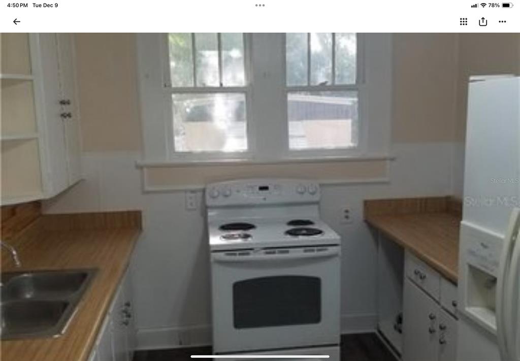 A kitchen features a white electric stove, wood-look countertops, and a double-basin stainless steel sink — 5612 WOODWARD AVENUE, ZELLWOOD, FL