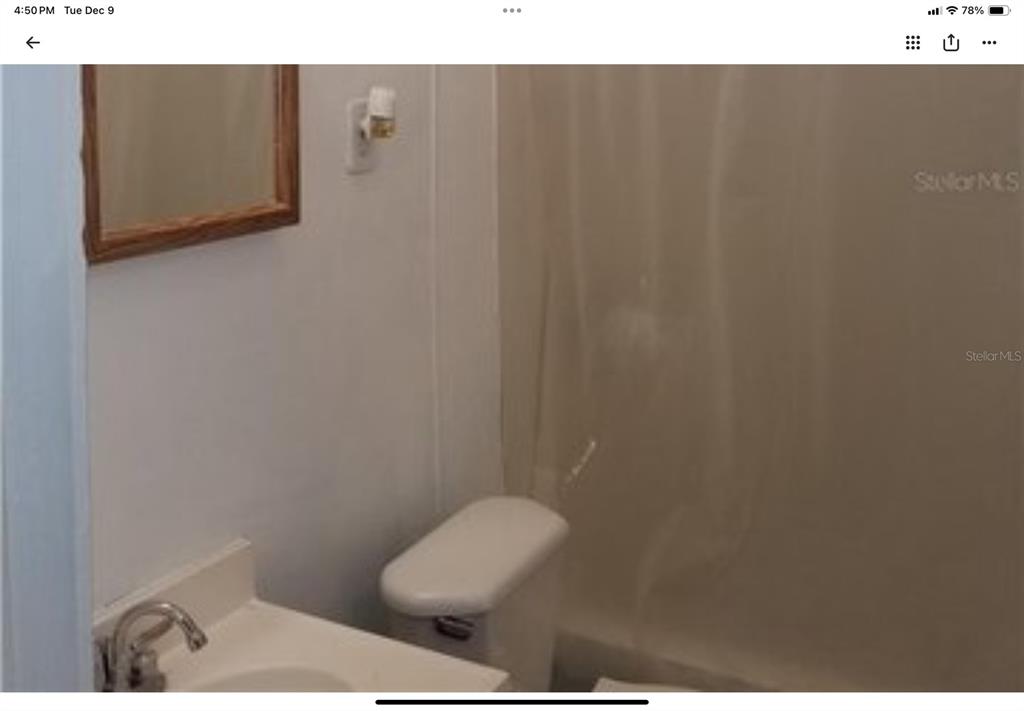 A bathroom features a vanity with a sink, a toilet, and a shower with curtains — 5612 WOODWARD AVENUE, ZELLWOOD, FL