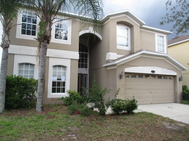 A two-story house with a tan stucco exterior, a two-car garage, and a palm tree — 20123 STILL WIND DRIVE, TAMPA, FL
