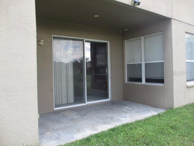A concrete patio sits outside a sliding glass door and a window on a house — 20123 STILL WIND DRIVE, TAMPA, FL