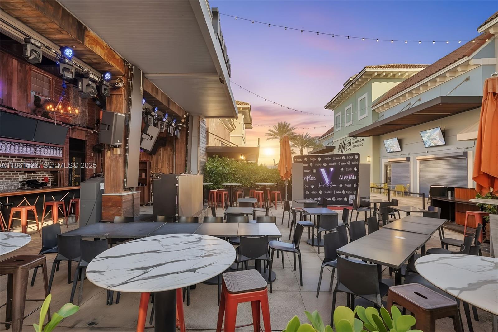 An outdoor patio area features tables, chairs, a bar, and a stage under string lights — Kendall Dr, Kendall FL 33183, KENDALL, FL