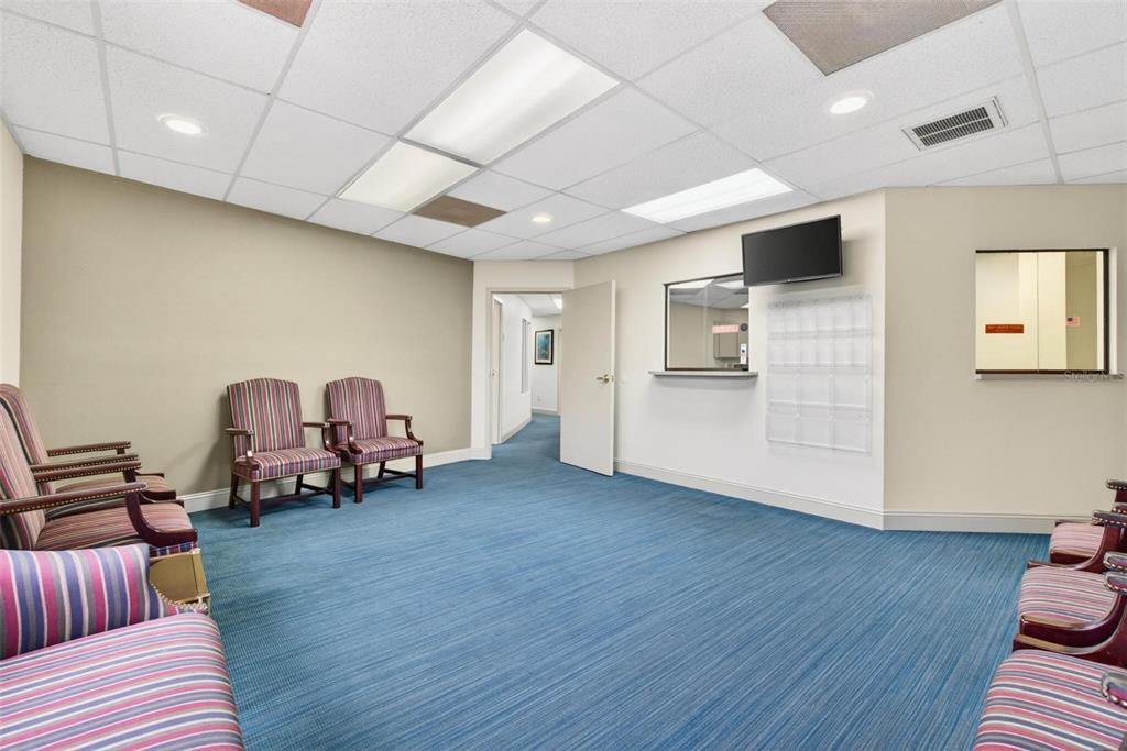A waiting room with blue carpet, striped chairs, a reception window, and a drop ceiling — 500 VONDERBURG DRIVE UNIT 314, BRANDON, FL