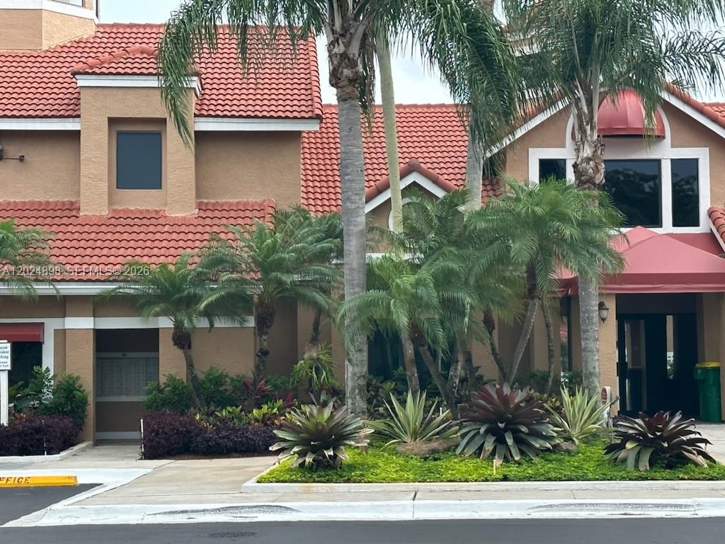 The exterior of a tan building features a red tile roof and palm trees — 15560 SW 104th Ter # 614, Miami FL 33196, MIAMI, FL