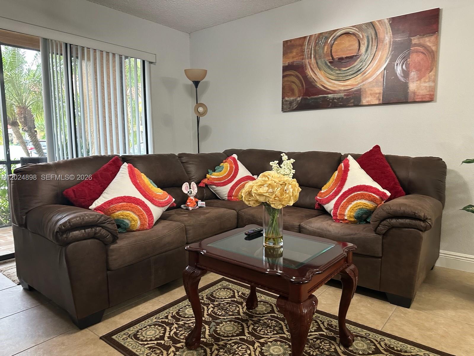 A living room features a brown sectional sofa, a glass-topped coffee table, and wall art — 15560 SW 104th Ter # 614, Miami FL 33196, MIAMI, FL