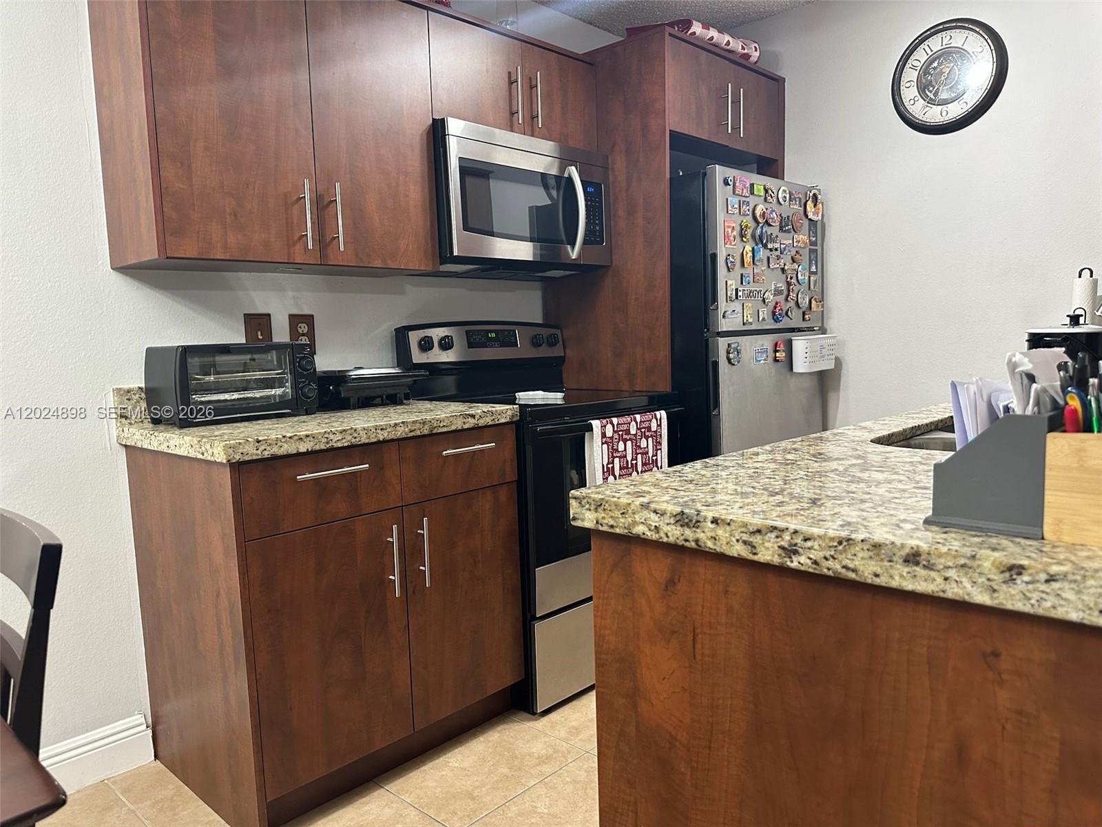 A kitchen features dark wood cabinets, granite countertops, stainless steel appliances, and a tiled floor — 15560 SW 104th Ter # 614, Miami FL 33196, MIAMI, FL