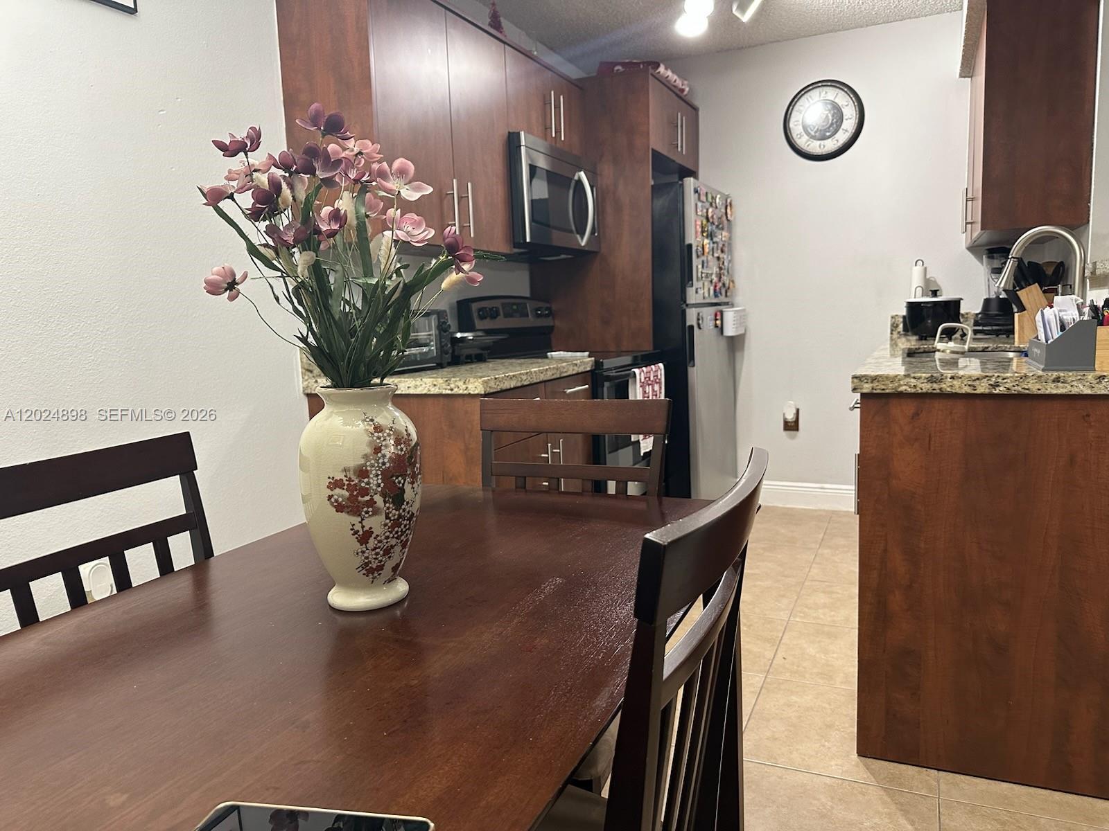 A dining area with a wooden table and chairs sits adjacent to a kitchen — 15560 SW 104th Ter # 614, Miami FL 33196, MIAMI, FL