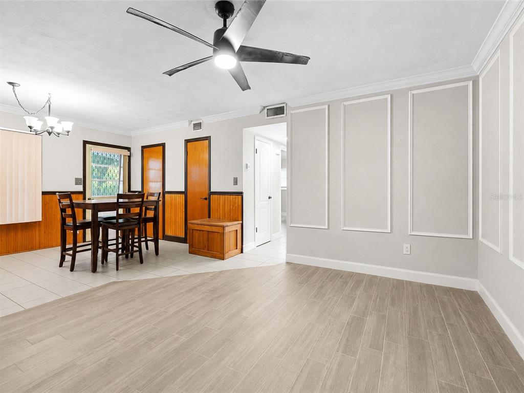 A dining area with wood wainscoting and a living space with light wood-look flooring — 5320 41ST AVENUE W, BRADENTON, FL