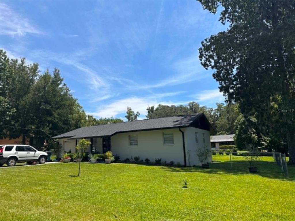 A single-story house with a white exterior, dark roof, and a large front lawn — 745 SE 29TH AVENUE, OCALA, FL