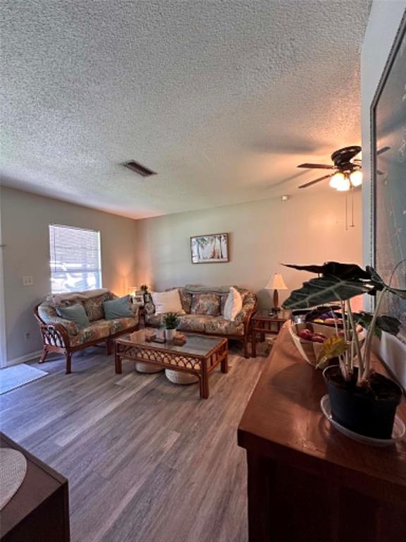 A living room with wood-look flooring, two wicker sofas, a glass-top coffee table, and a ceiling fan — 745 SE 29TH AVENUE, OCALA, FL