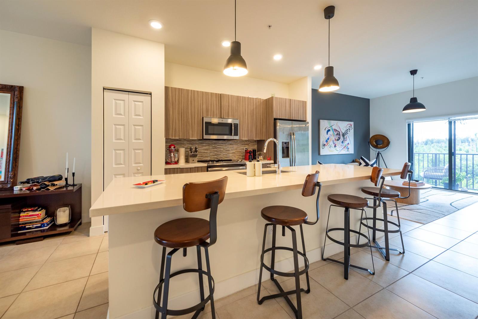 A modern kitchen features a large island with bar seating, wood cabinetry, and stainless appliances — 7925 NW 104th Avenue # 24, Doral FL 33178, DORAL, FL
