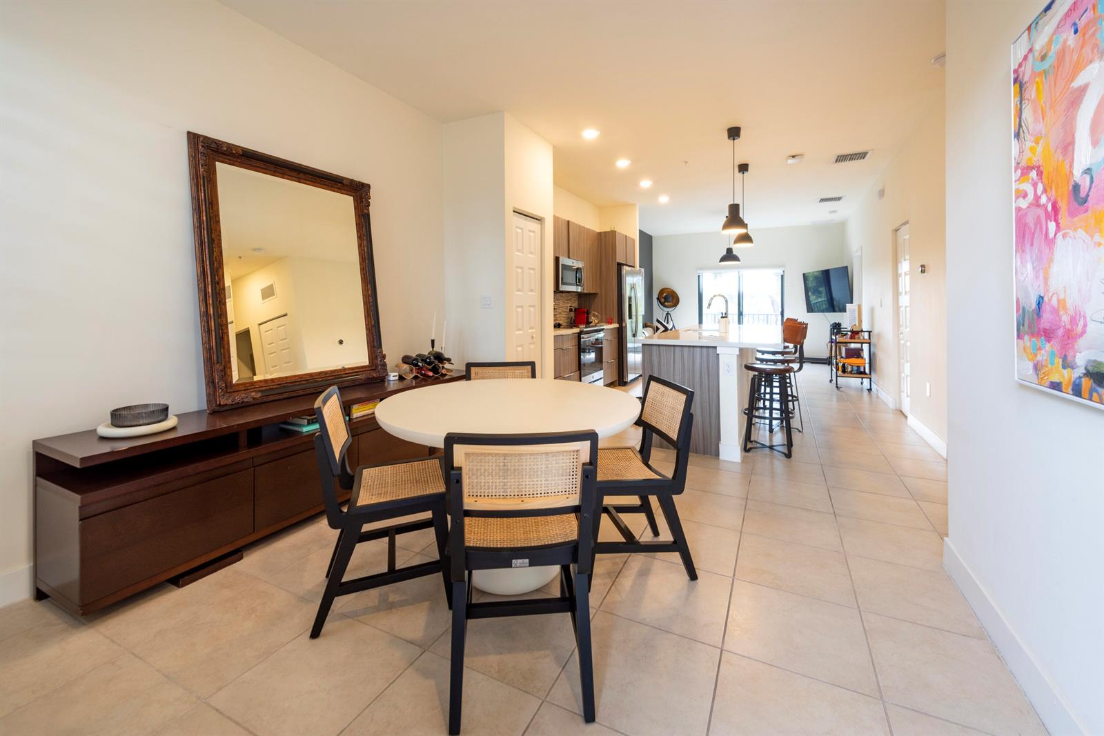 A dining area with a round table and cane chairs sits before an open kitchen — 7925 NW 104th Avenue # 24, Doral FL 33178, DORAL, FL