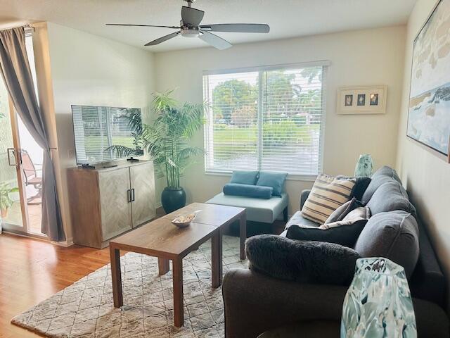 A living room features a gray sofa, wooden coffee table, television console, and large window — 402 Villa Circle # 402, Boynton Beach FL 33435, BOYNTON BEACH, FL