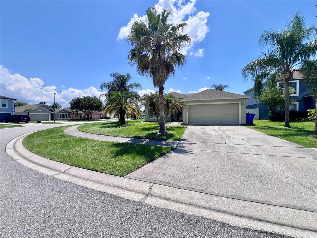 A single-story suburban house features a two-car garage, a concrete driveway, and several palm trees — 2950 ELBIB DRIVE, ST CLOUD, FL