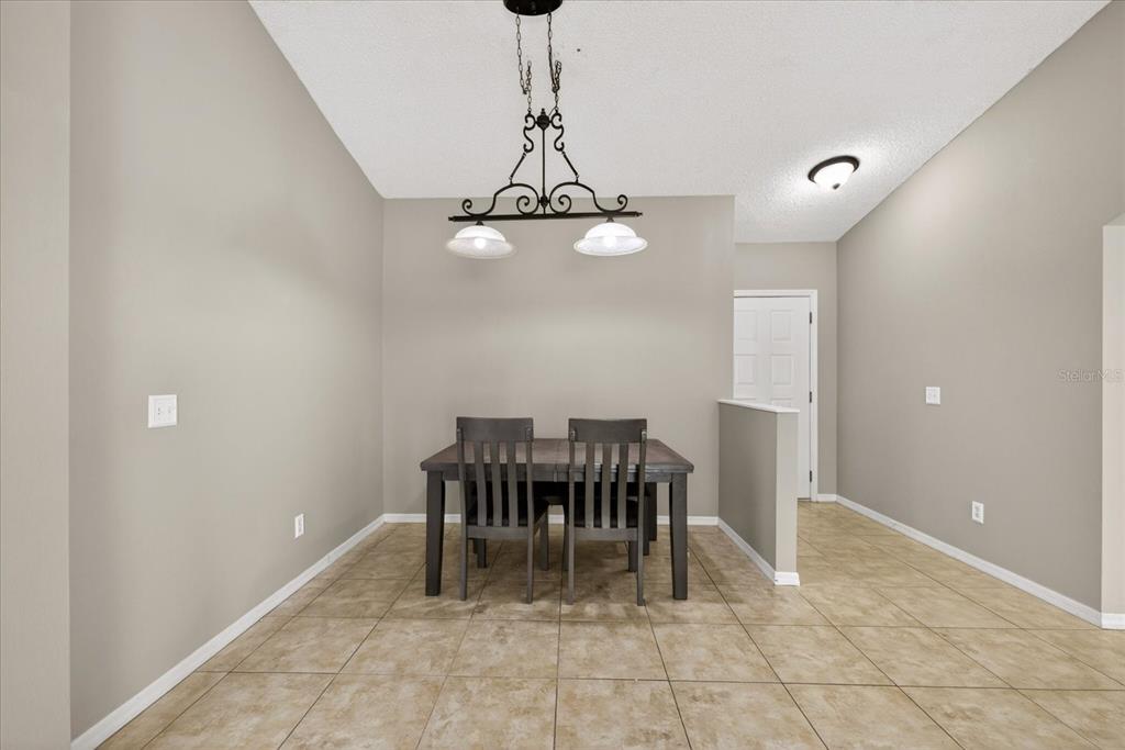 A dining area features a dark wood table with two chairs under a metal chandelier — 12015 CEDARFIELD DRIVE, RIVERVIEW, FL