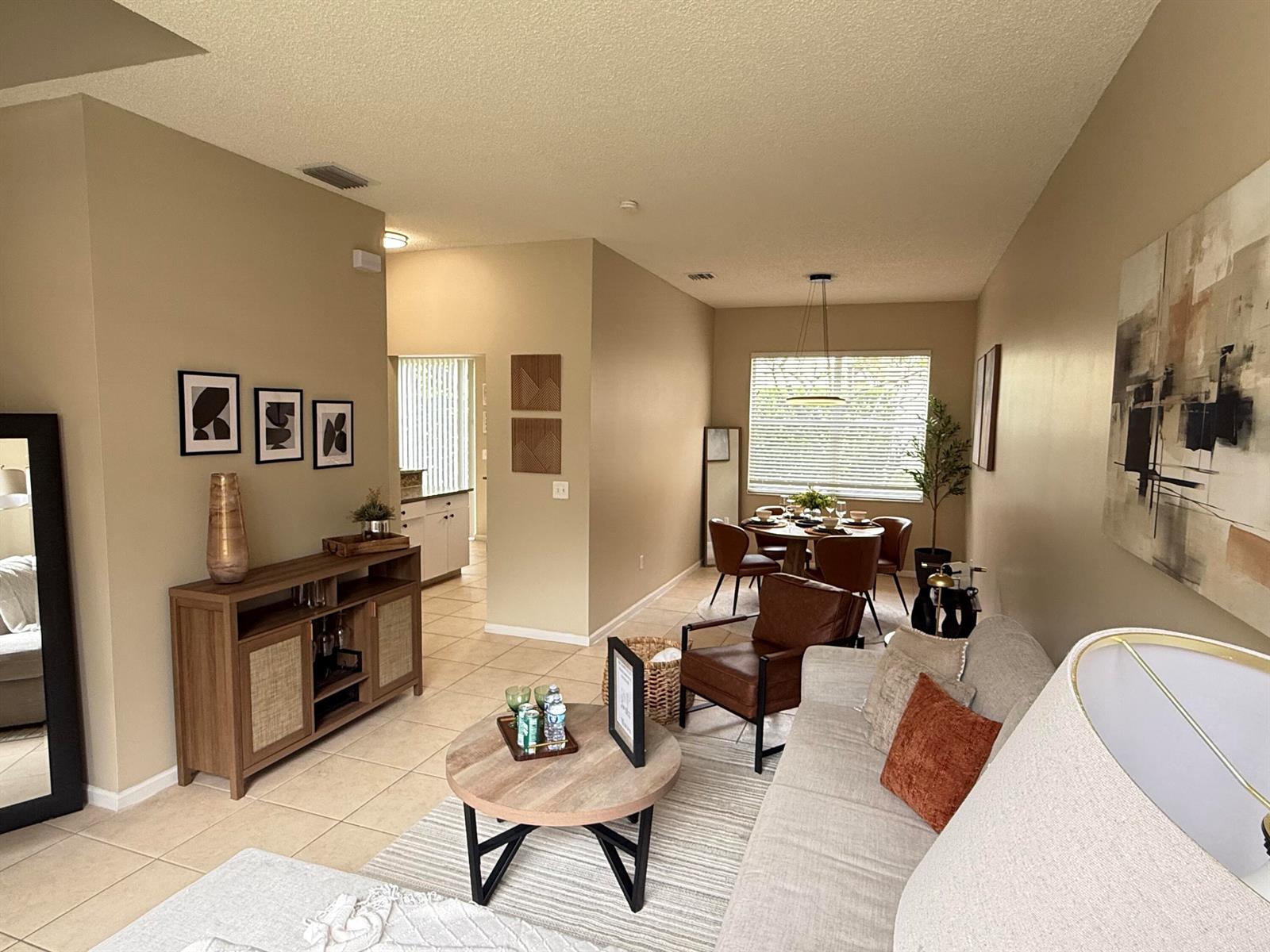 A living room and dining area feature beige walls, tile flooring, and modern furniture — 5203 Eagle Cay Place, Coconut Creek FL 33073, COCONUT CREEK, FL