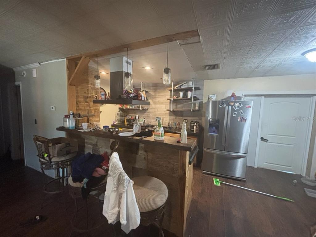 A kitchen features a wooden breakfast bar, stainless steel refrigerator, and open shelving — 11529 107TH AVENUE, LARGO, FL