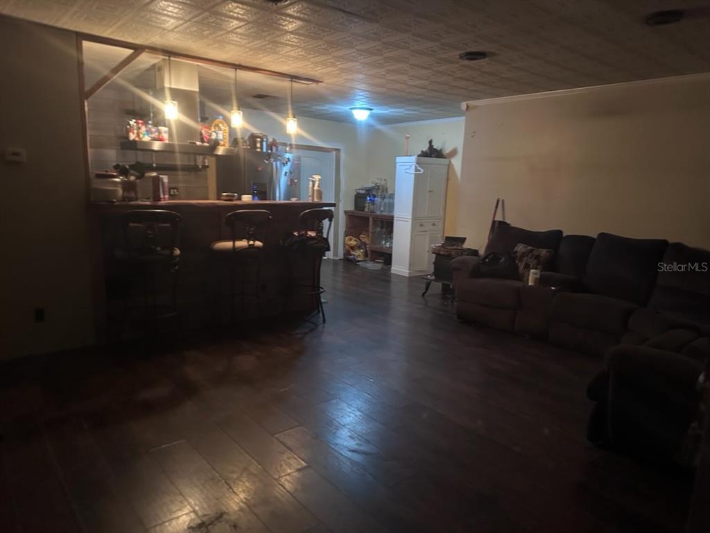 A living room with dark wood flooring, a breakfast bar, and a patterned ceiling — 11529 107TH AVENUE, LARGO, FL