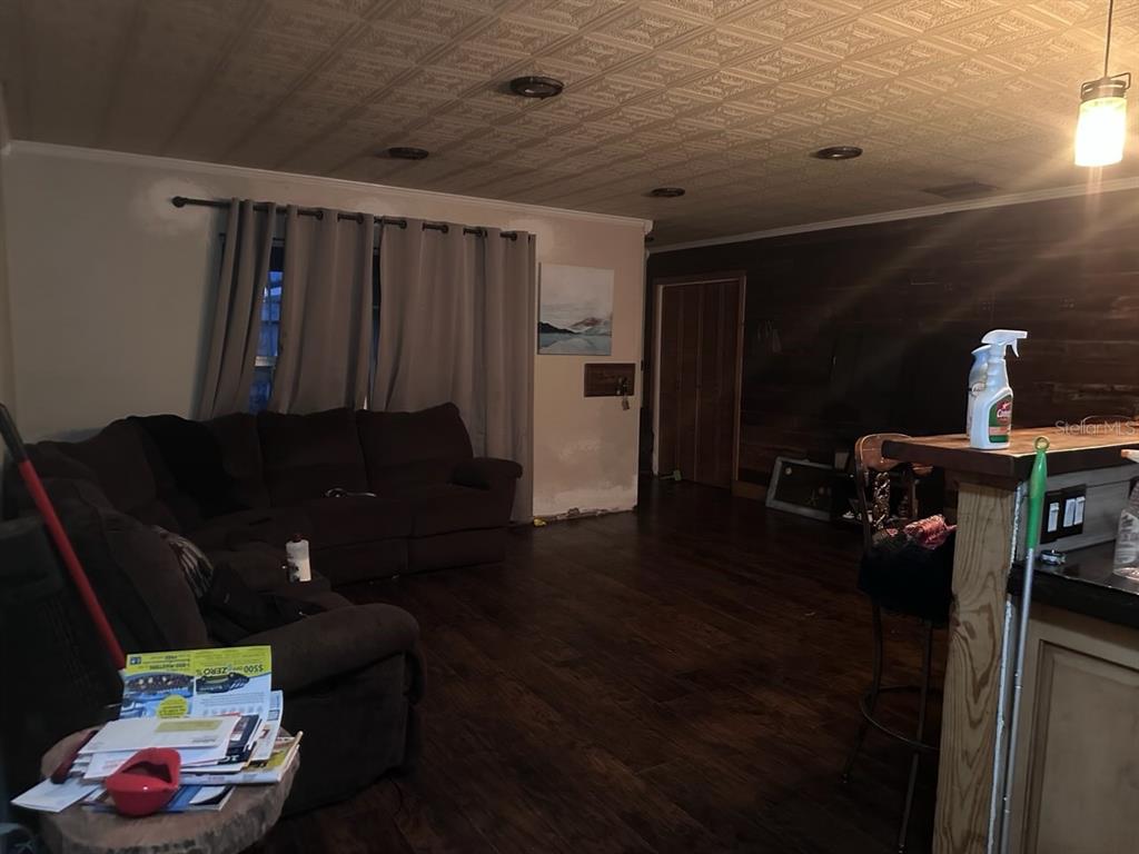 A living room features dark wood flooring, a textured ceiling, and a large brown sectional sofa — 11529 107TH AVENUE, LARGO, FL