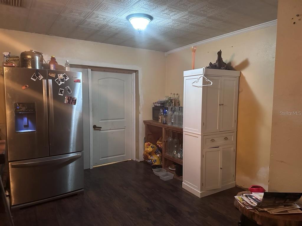A kitchen features a stainless steel refrigerator, a white cabinet, and a wooden bar area — 11529 107TH AVENUE, LARGO, FL