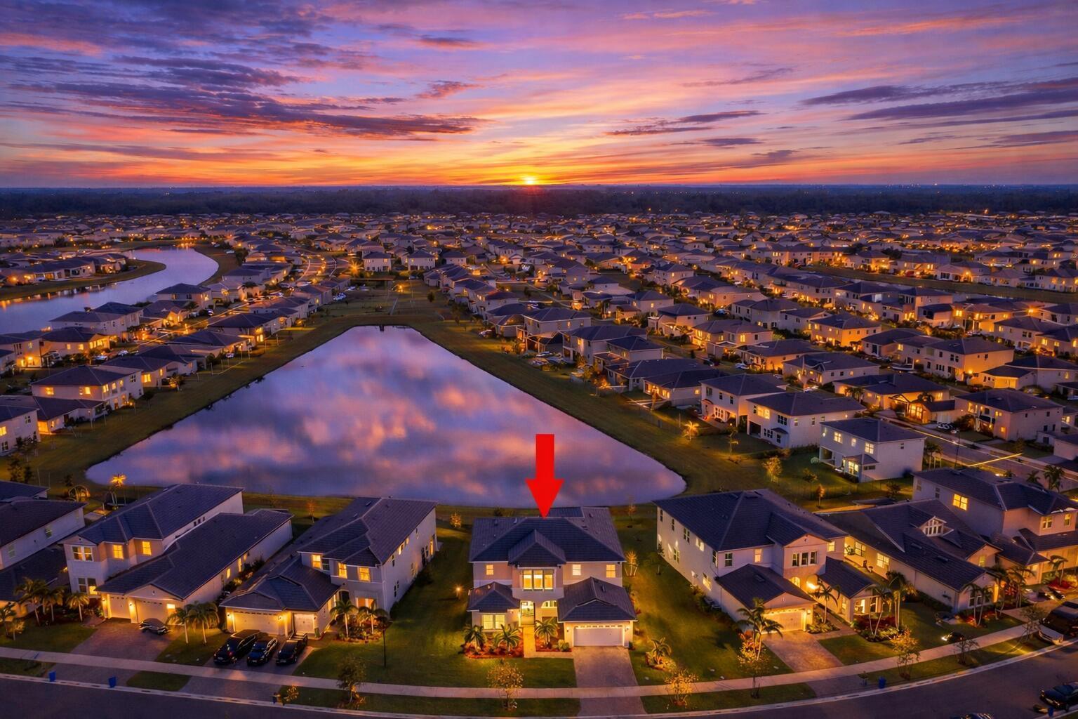 An aerial view of a suburban house at sunset, featuring a lake and surrounding neighborhood — 5338 Liberty Lane, FL 33470, FL