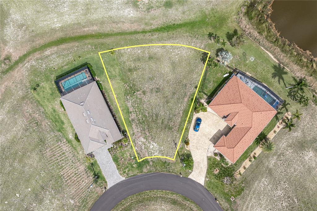 An aerial view shows a vacant, trapezoidal residential lot situated between two houses with pools — 17528 VELLUM CIRCLE, PUNTA GORDA, FL