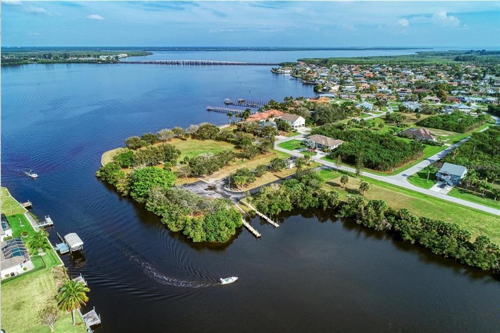 An aerial view shows a waterfront property with a boat ramp, docks, and nearby houses — 12084 BEIMAN AVENUE, PORT CHARLOTTE, FL