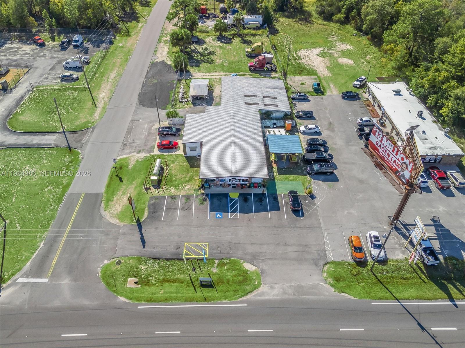 An aerial view shows a commercial building with a parking lot and billboard — 9594 SE Maricamp Road, Ocala FL 34472, OCALA, FL