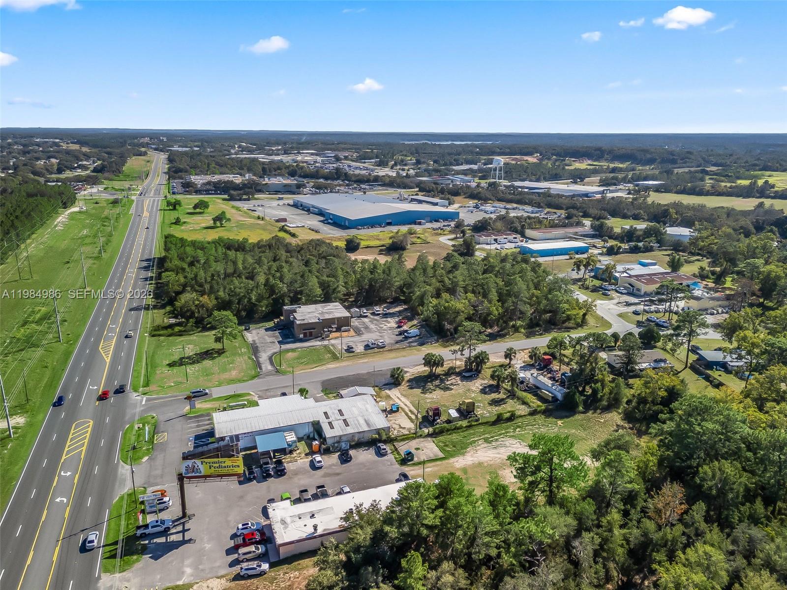 An aerial view shows a commercial building with a parking lot next to a highway — 9594 SE Maricamp Road, Ocala FL 34472, OCALA, FL