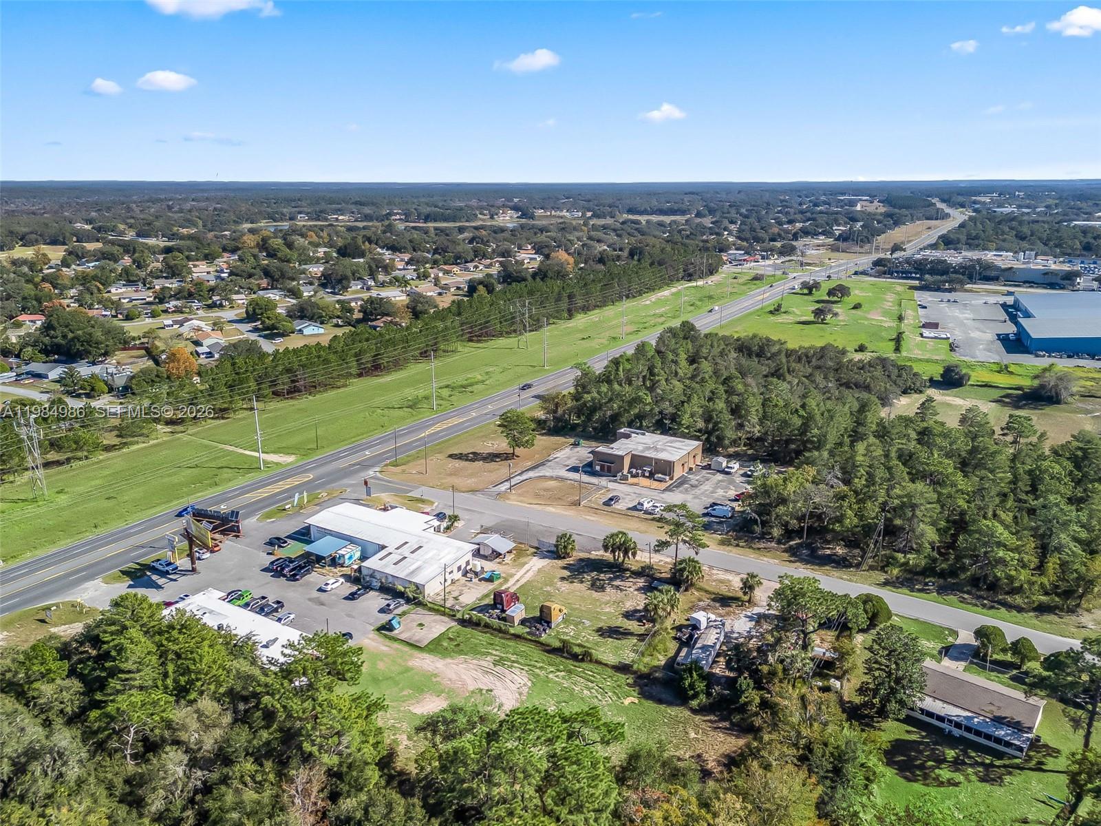 An aerial view shows commercial buildings, a highway, and surrounding wooded residential areas — 9594 SE Maricamp Road, Ocala FL 34472, OCALA, FL