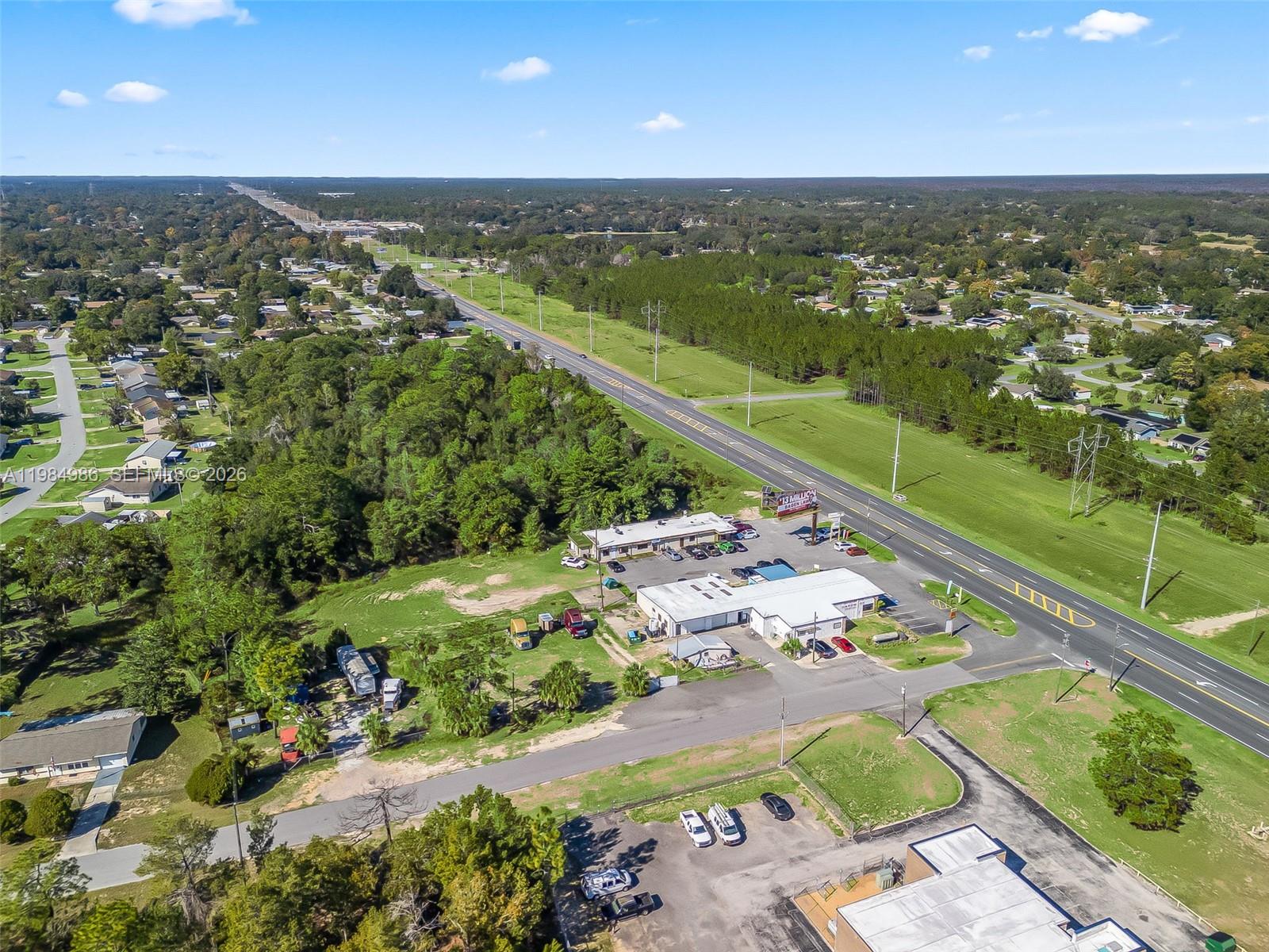 An aerial view shows commercial buildings, a parking lot, and a highway surrounded by trees — 9594 SE Maricamp Road, Ocala FL 34472, OCALA, FL