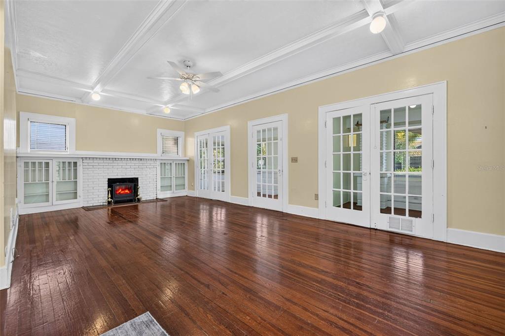 A spacious living room features hardwood floors, a white brick fireplace, and multiple French doors — 2800 2ND AVENUE N, ST PETERSBURG, FL