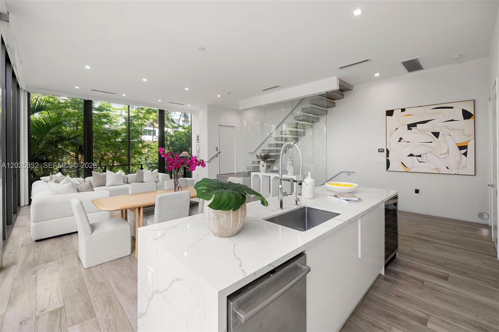 A modern kitchen with a white marble island overlooks a living area with floor-to-ceiling windows — 1525 Bay Rd, Miami Beach FL 33139, MIAMI BEACH, FL
