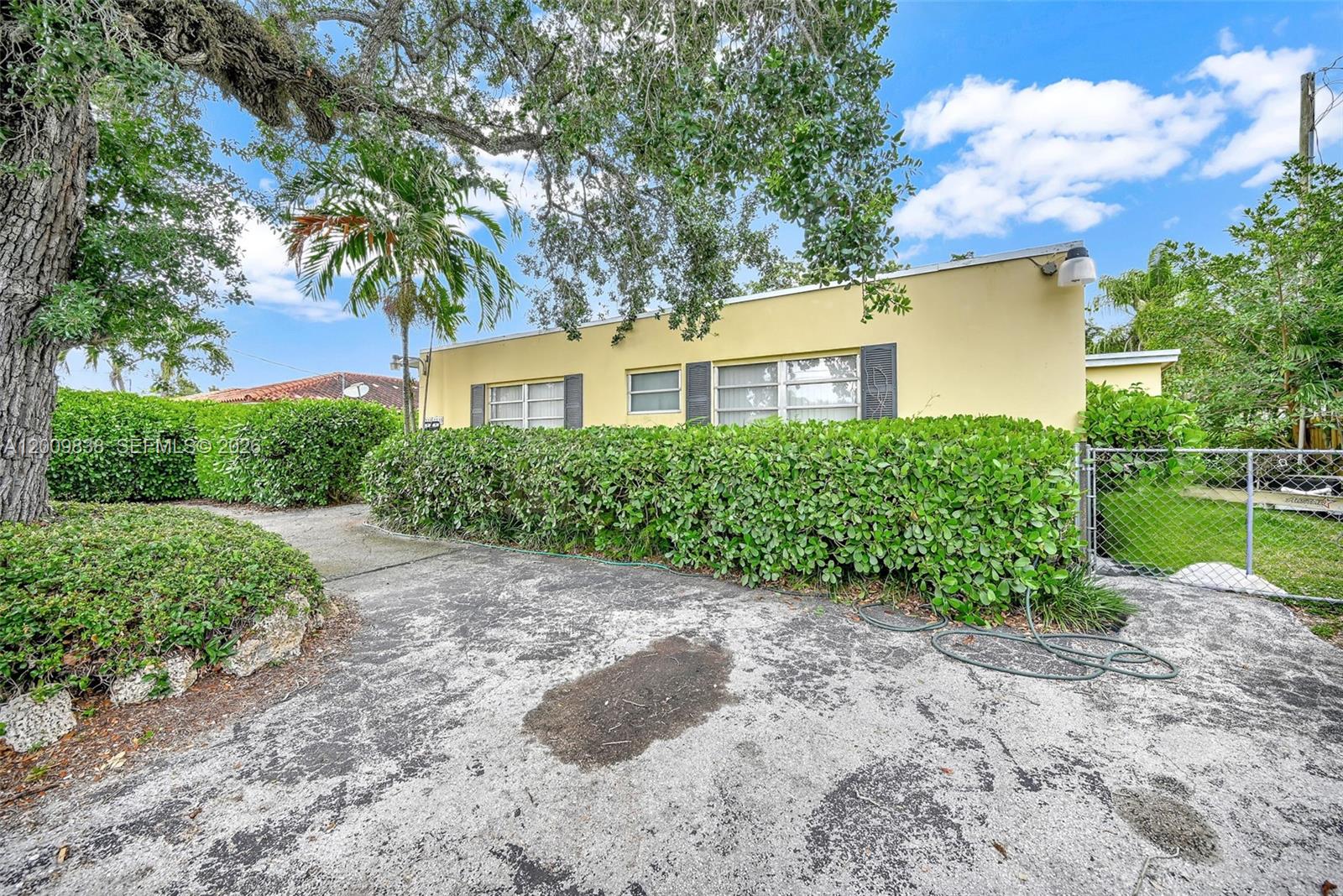 A yellow single-story house with a paved driveway and a large hedge in front — 2225 SW 62nd Ct # 2225, Miami FL 33155, MIAMI, FL