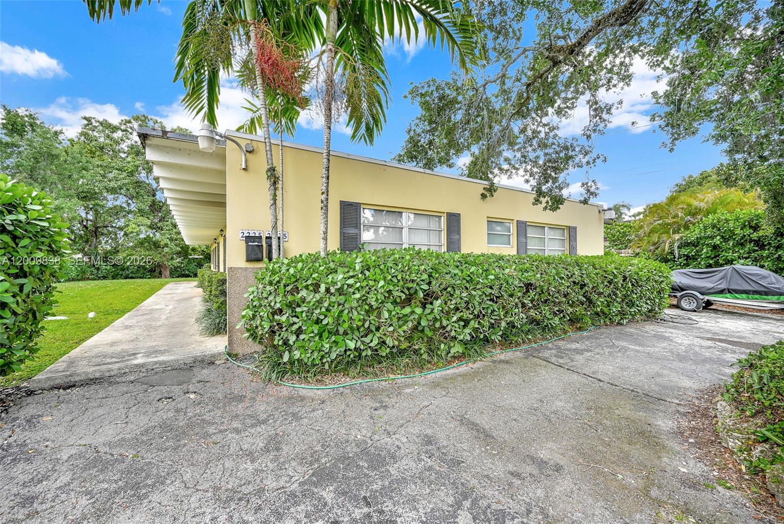 A yellow single-story house with a flat roof, concrete driveway, and large privacy hedge — 2225 SW 62nd Ct # 2225, Miami FL 33155, MIAMI, FL