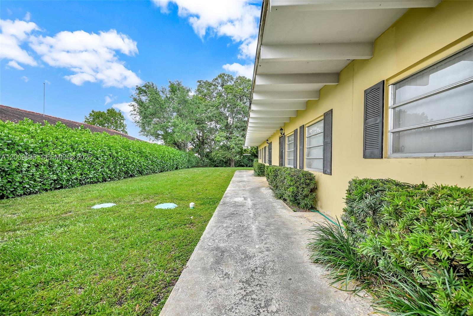 A yellow building exterior features a concrete walkway, green hedges, and a grassy lawn — 2225 SW 62nd Ct # 2225, Miami FL 33155, MIAMI, FL