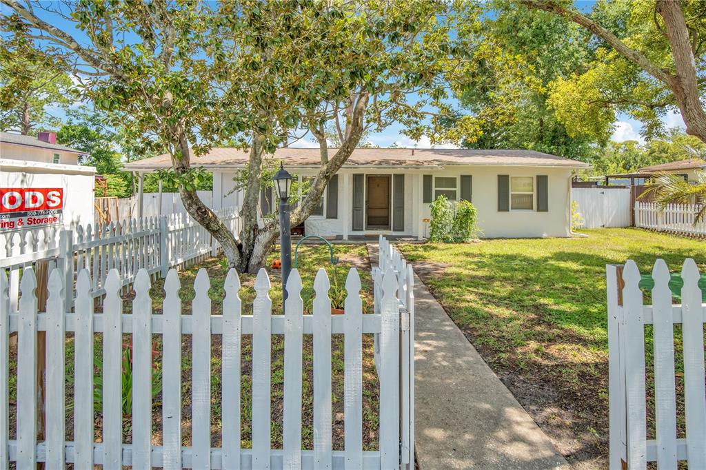 A single-story house with a white picket fence and a storage container in the yard — 682 MERRIMAC STREET, DELTONA, FL