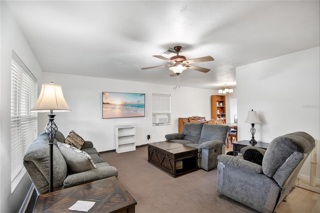 A living room features gray furniture, a ceiling fan, a wall-mounted television, and carpeted floors — 682 MERRIMAC STREET, DELTONA, FL
