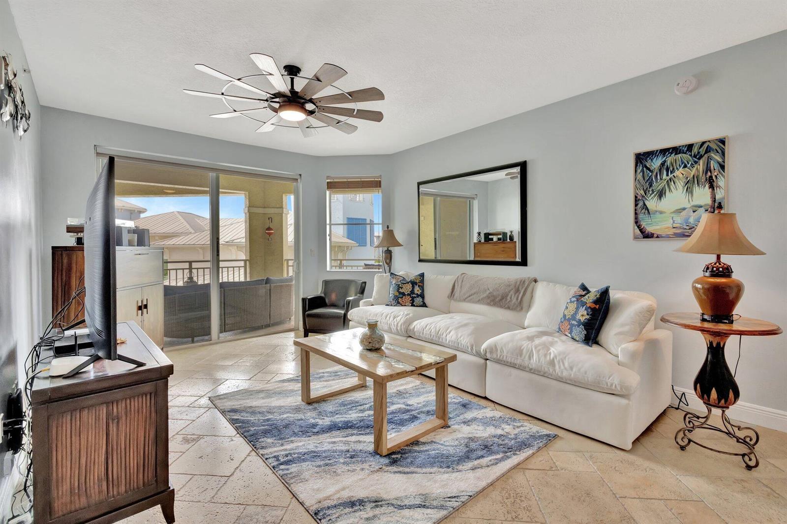 A living room features a white sofa, a wooden coffee table, and a ceiling fan — 975 NW Flagler Avenue # 407, Stuart FL 34994, STUART, FL