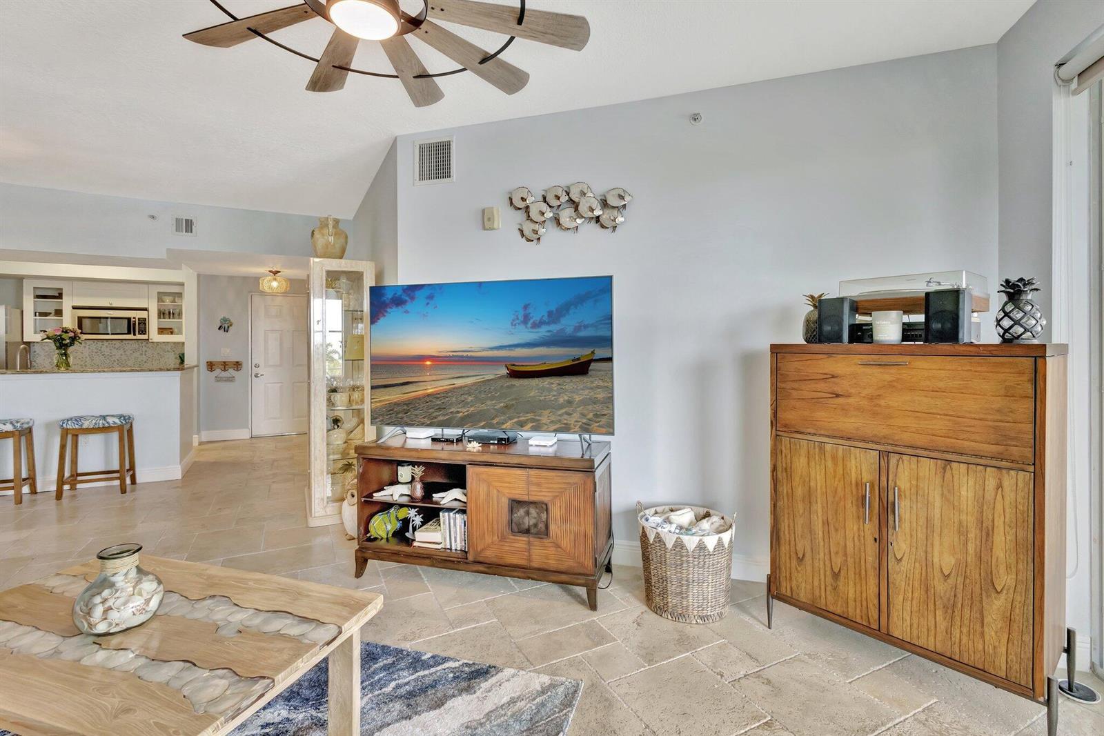 A living room features a television on a wooden stand, a cabinet, and tile flooring — 975 NW Flagler Avenue # 407, Stuart FL 34994, STUART, FL