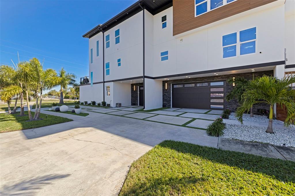 A modern three-story house features a concrete driveway, a garage, and palm trees — 6062 BAYOU GRANDE BOULEVARD NE, ST PETERSBURG, FL