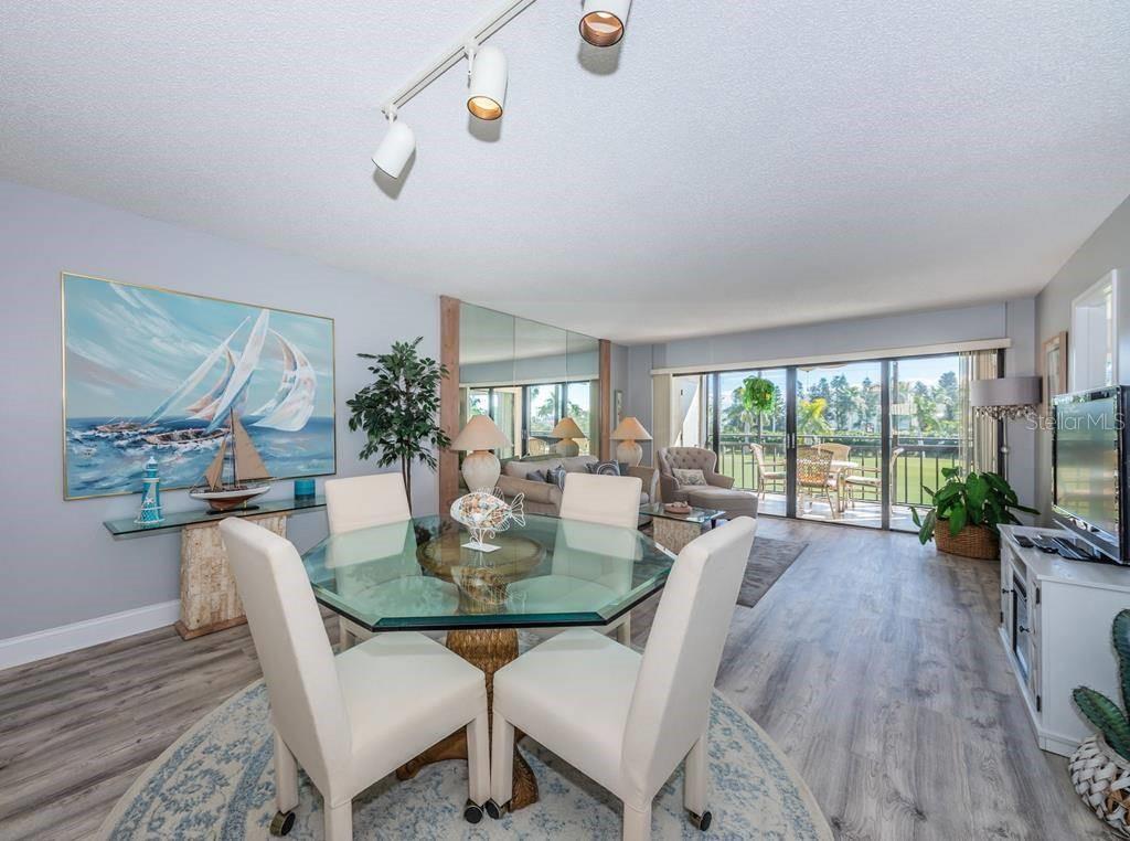 A dining area with a glass table and chairs sits before a living room with balcony access — 5724 PUERTA DEL SOL BOULEVARD S UNIT 248, ST PETERSBURG, FL