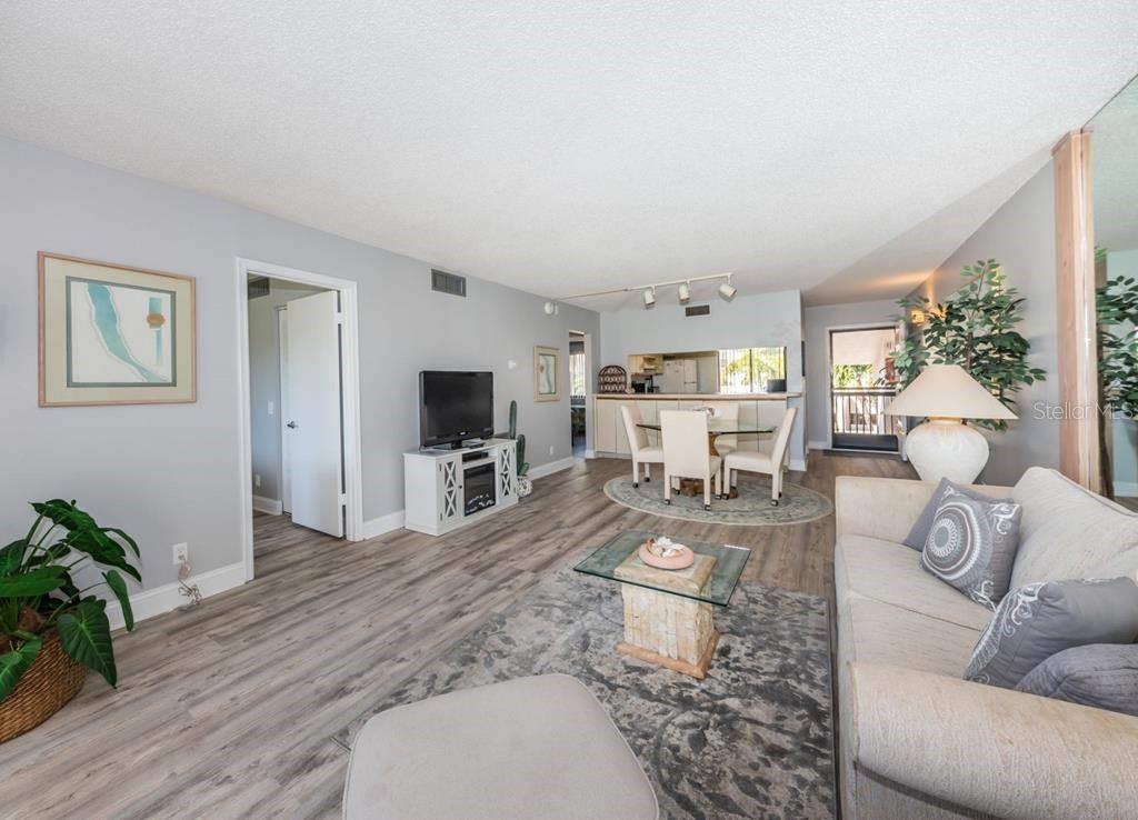 A living room with light wood-look flooring, a dining area, and a neutral-toned sofa — 5724 PUERTA DEL SOL BOULEVARD S UNIT 248, ST PETERSBURG, FL