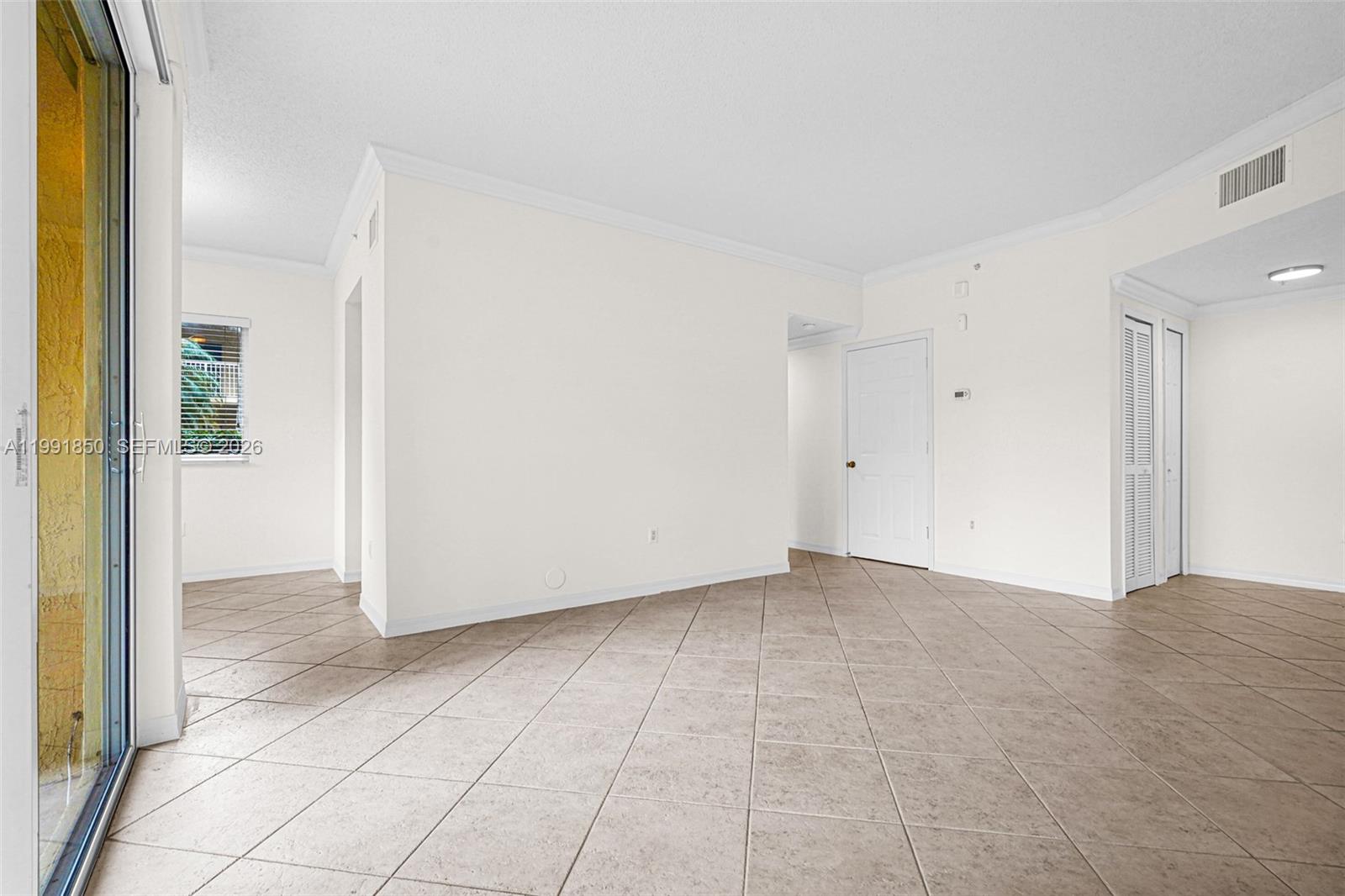 An empty room with beige tile flooring, white walls, and a sliding glass door — 7085 Nova Dr # 128, Davie FL 33317, DAVIE, FL